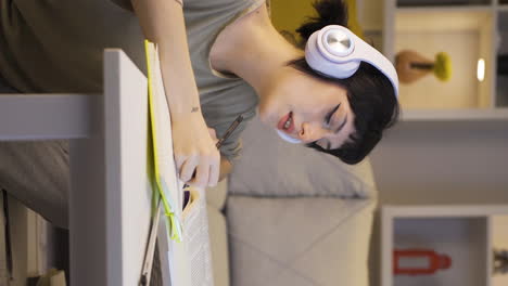 Vertical-video-of-Female-student-listening-to-music-and-studying-at-night.